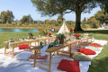Red and white luxury picnic setup by lake.