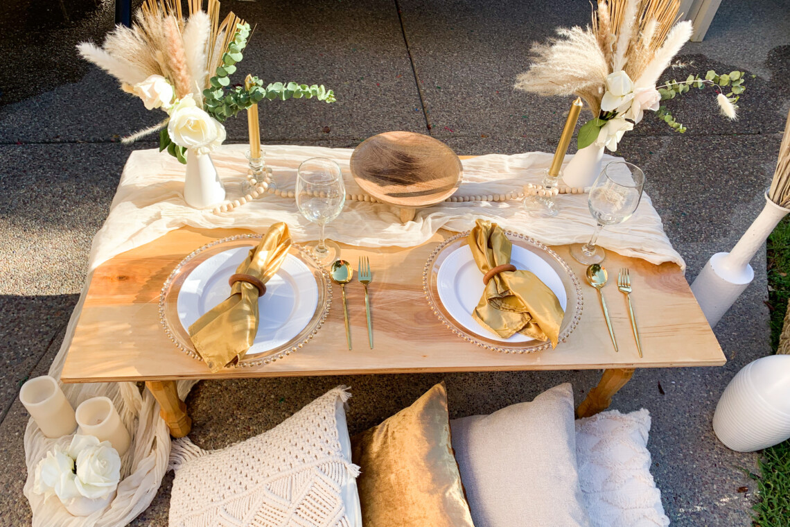 Picnic Set Up decorated with golden napkins, pillows, cutlery, and pampas.