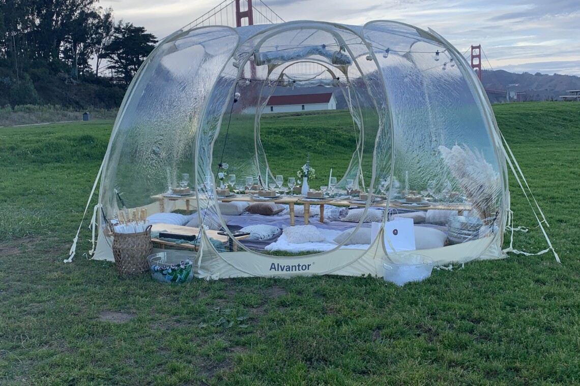 Luxury picnic set up inside a bubble tent overlooking the Golden Gate Bridge in San Francisco, California.