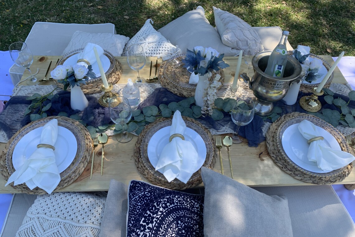 Top view of a blue themed picnic with golden napkin rings and cutlery.